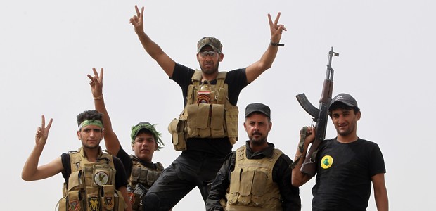 Iraqi Shiite fighters from the Popular Mobilisation units flash the "V" for victory sign in the town of Baiji, north of Tikrit, as they fight alongside Iraqi forces against the Islamic State (IS) jihadist group to try to retake the strategic northern Iraqi town for a second time, on June 10, 2015. Baghdad regained control of Baiji -- located on the road to IS hub Mosul and near the country's largest oil refinery -- last year, but subsequently lost it again. AFP PHOTO / AHMAD AL-RUBAYE        (Photo credit should read AHMAD AL-RUBAYE/AFP/Getty Images)